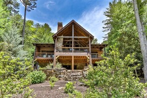 A two-story log cabin with a stone foundation, wooden balconies, and a forested backdrop. - Around The Bend On Lake Blue Ridge | Blue Ridge, G (Blue Ridge)
