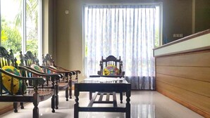 A room with a long wooden bench, a table, and a chair with a colorful cushion. - Hotel O Rumah Massagena Syariah Near Gedung Olahraga Enrekang (Makassar)