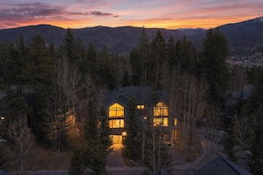 A cabin surrounded by dense forest with a clear view of the mountains in the background.