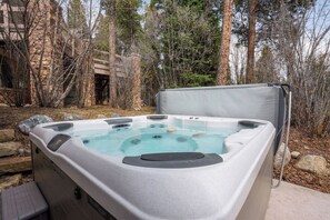 A hot tub with a stone structure and trees in the background.
