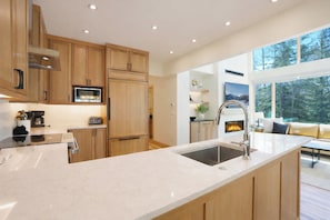 A modern kitchen with wooden cabinets, a built-in microwave, and a large island with a sink.