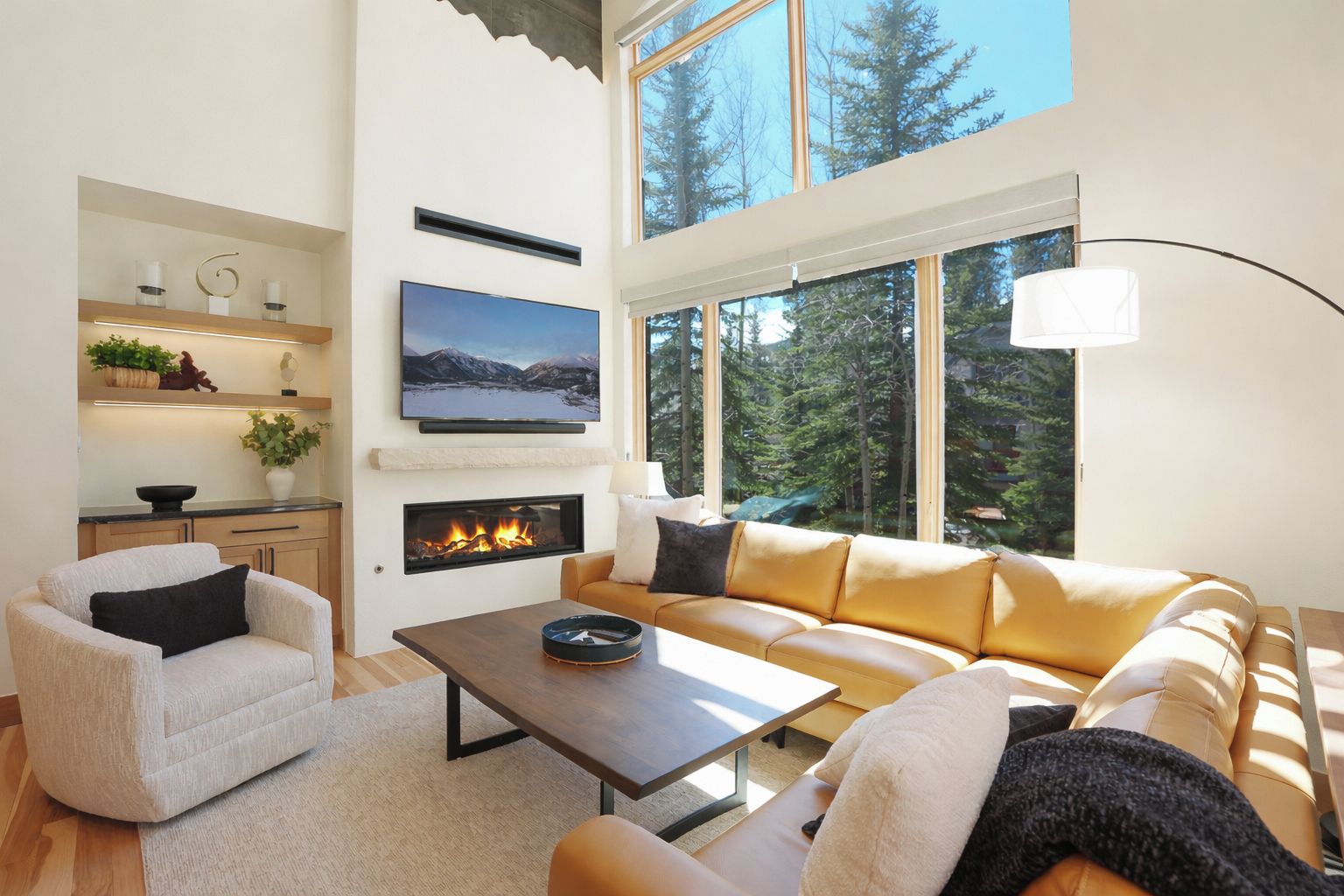 A modern living room with a fireplace, a sofa, a coffee table, and a TV mounted on the wall.
