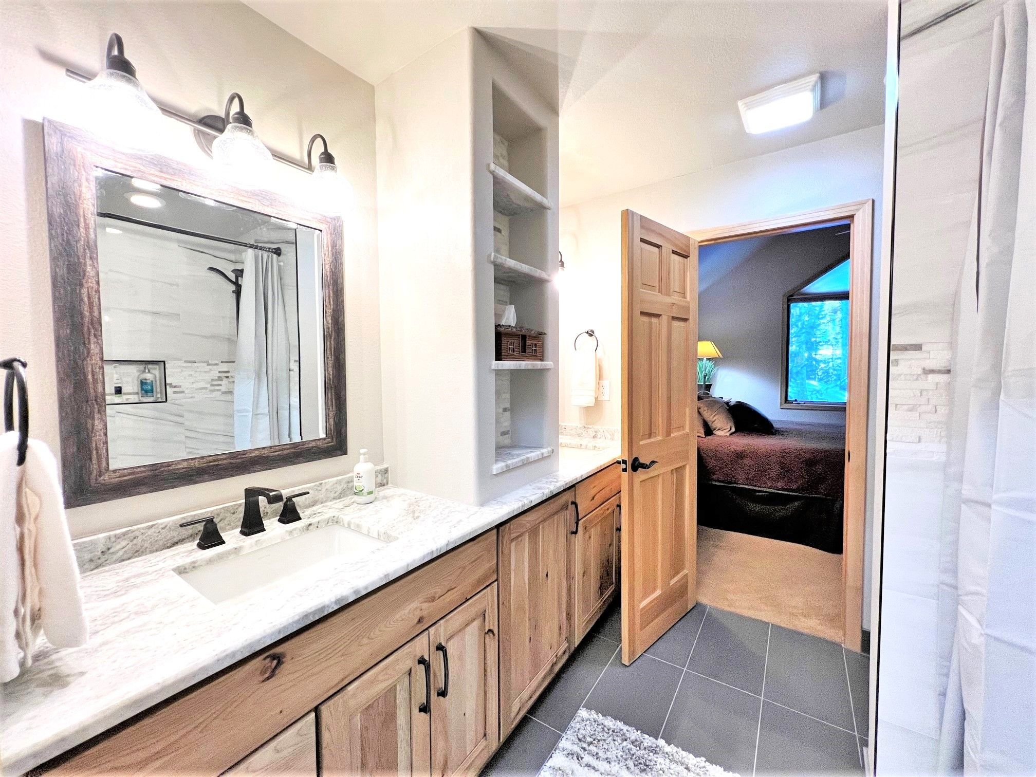 Une salle de bain dotée d’un grand miroir, de deux lavabos, de meubles en bois et d’un espace douche.