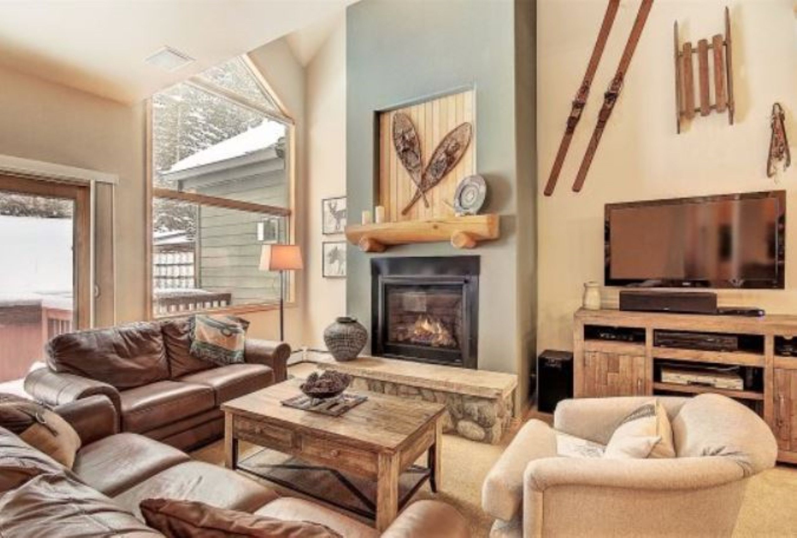 Una sala de estar acogedora con chimenea, sofás de cuero, una mesa de centro y una televisión.