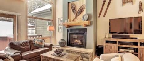 Una sala de estar acogedora con chimenea, sofás de cuero, una mesa de centro y una televisión.
