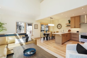 A modern living room with a sofa, coffee table, and dining area.