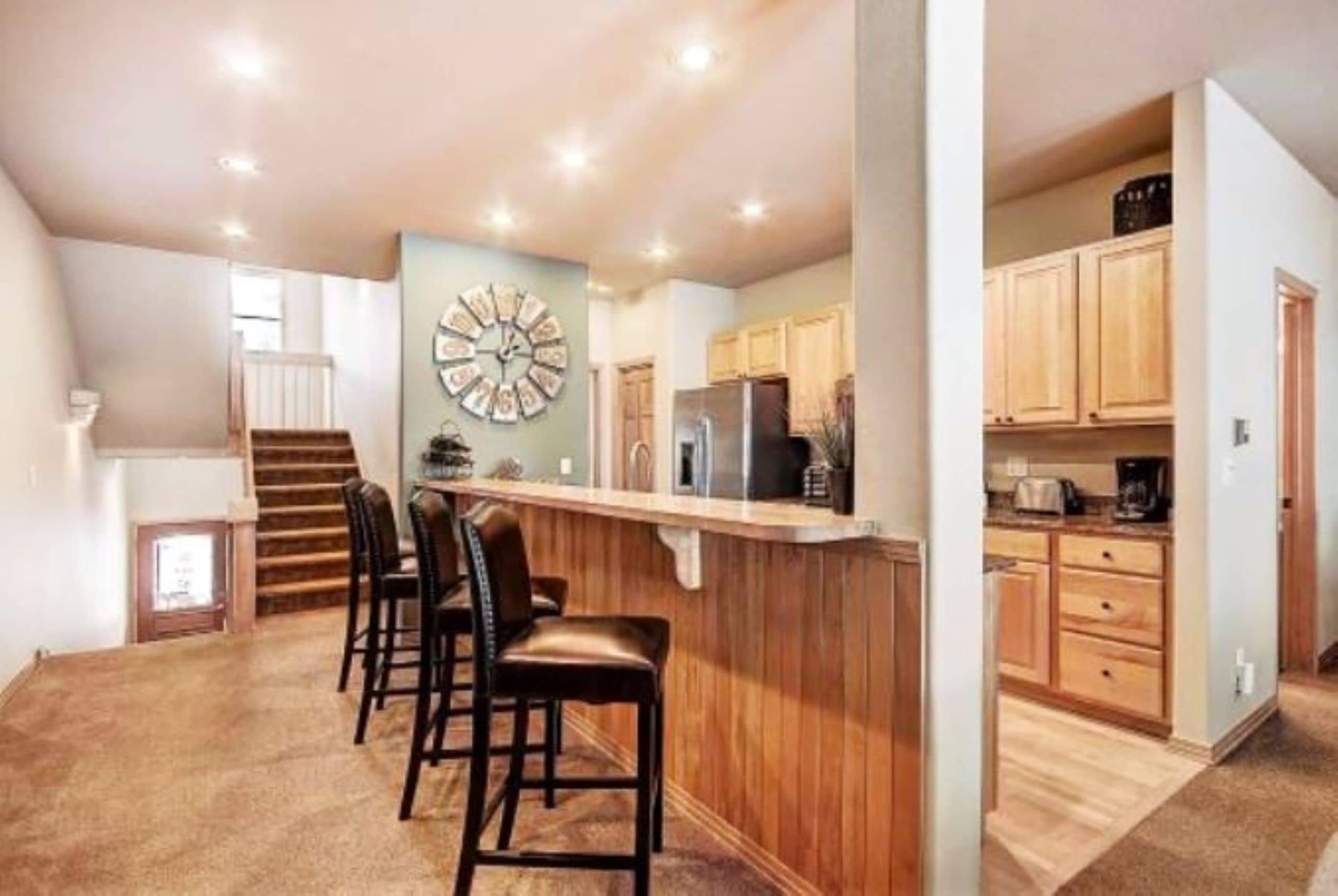 A spacious kitchen with wooden cabinets, a central island, and a clock on the wall.