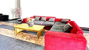 Un salon avec un canapé rouge, une table basse jaune et une plante en pot.