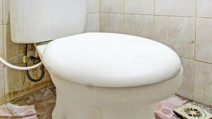 Des toilettes dans une salle de bain dont le sol et les murs sont recouverts de carrelage.