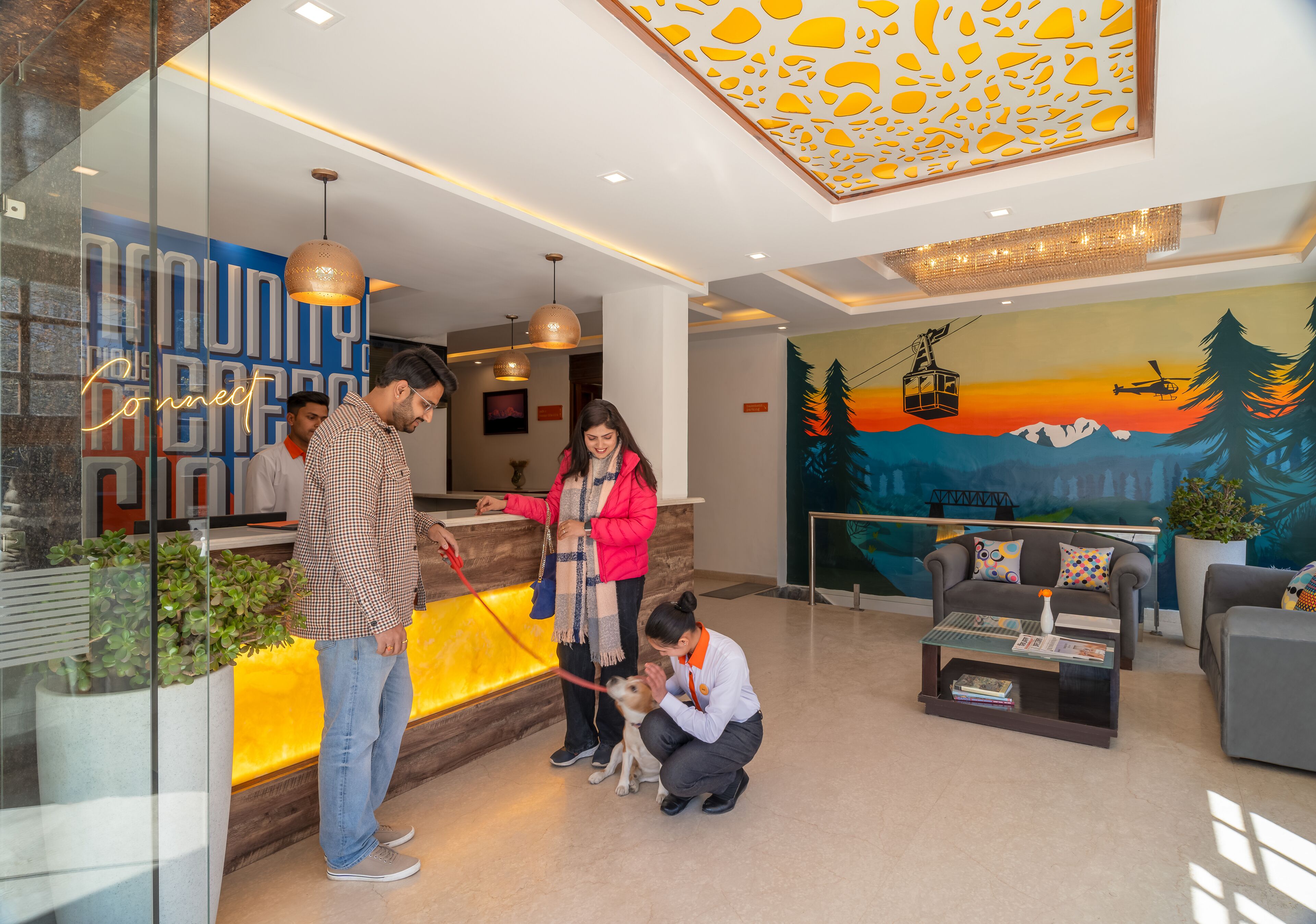 A reception area with a modern design, including a reception desk, a mural depicting a sunset, and a seating area with a coffee table.