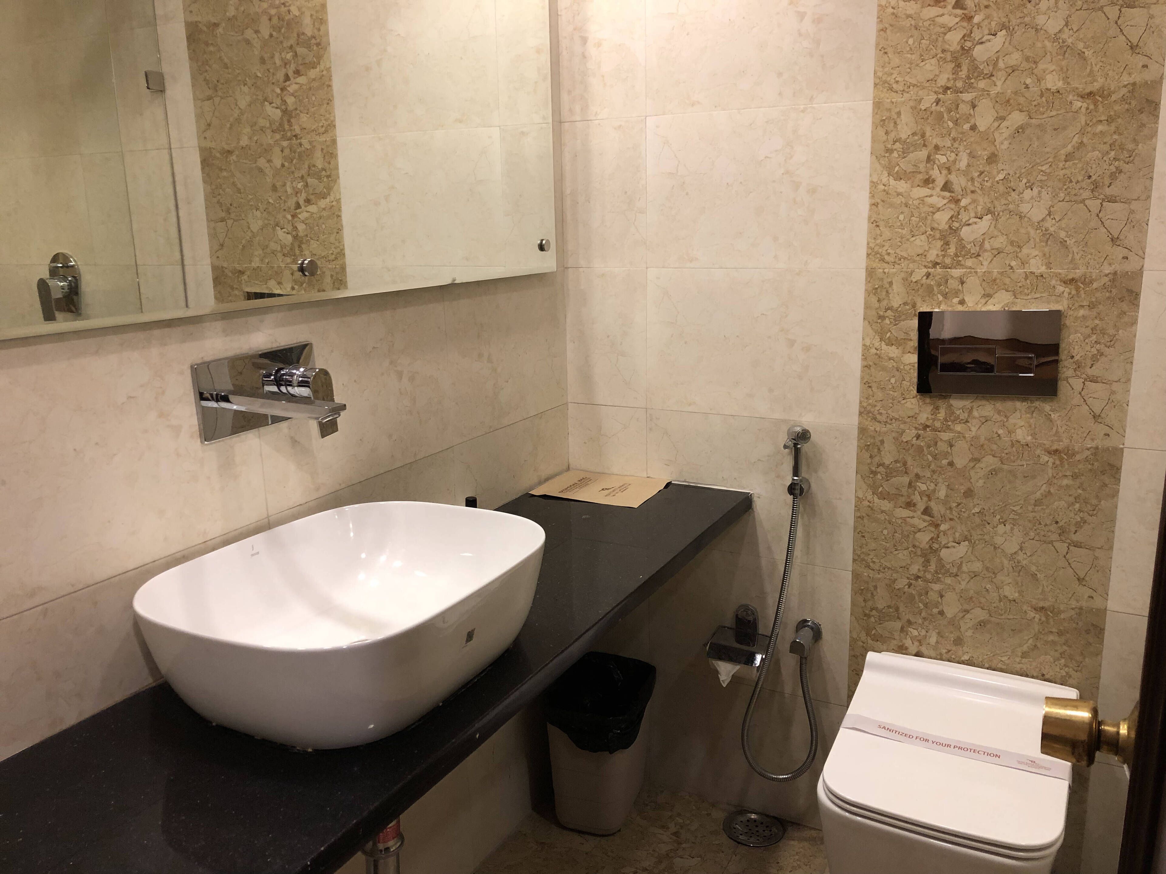 A bathroom with a white sink, a mirror, a toilet, and a shower.