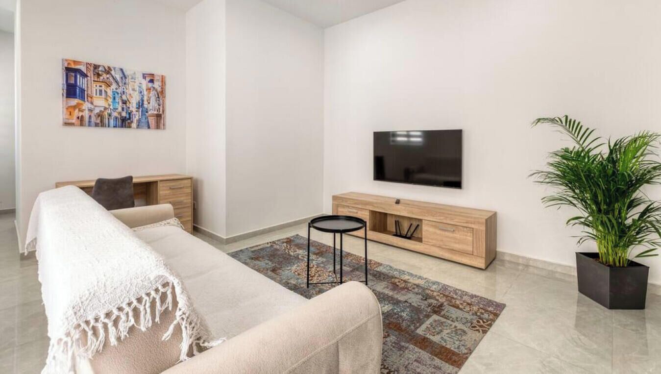 Uma sala de estar moderna com um sofá, TV, armário de madeira e uma planta em vaso.