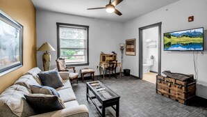 A living room with a sofa, coffee table, and a television mounted on the wall. - Webber Hotel (Lyndonville)