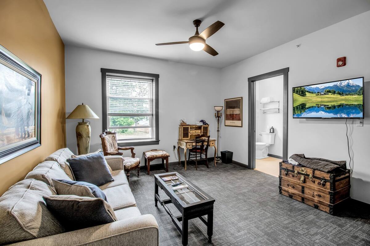 A living room with a sofa, coffee table, and a television mounted on the wall.