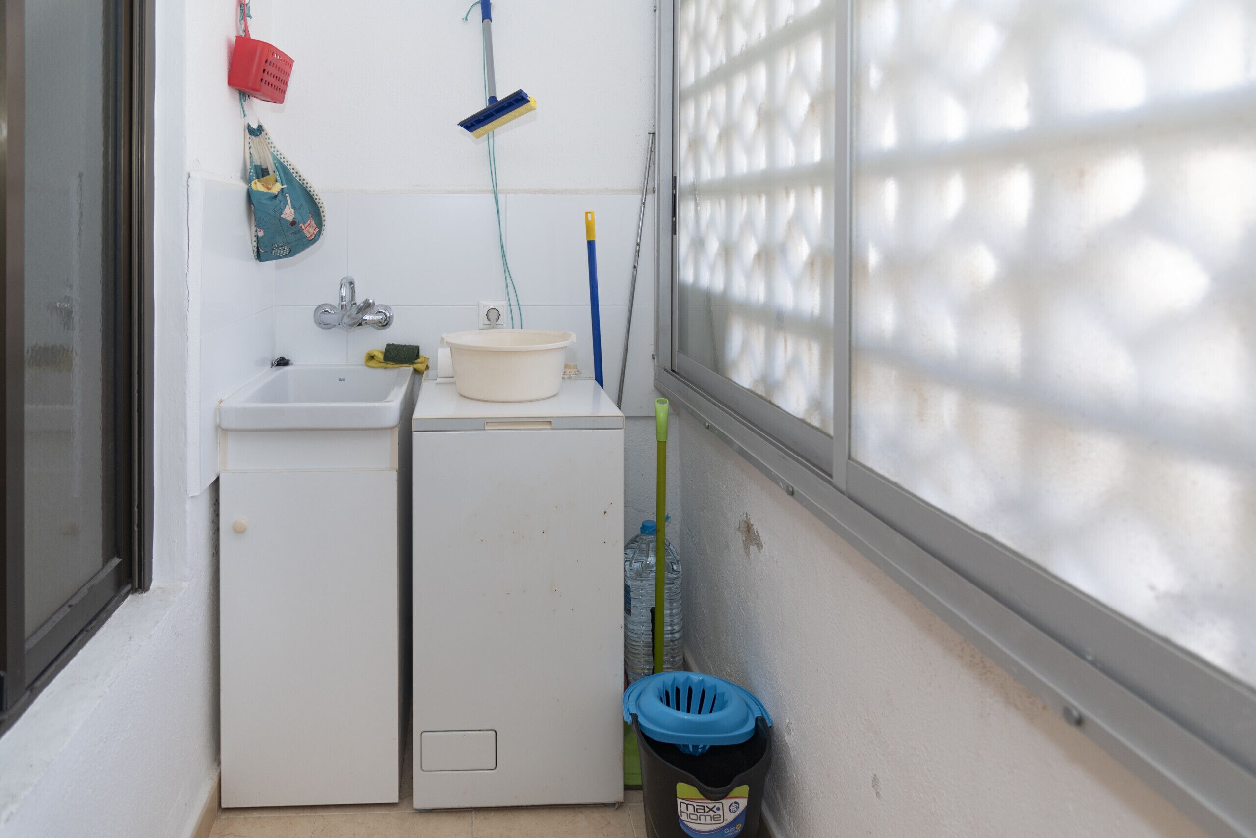 A small laundry area with a washing machine, a sink, and a drying rack.