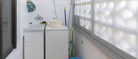 A small laundry area with a washing machine, a sink, and a drying rack.