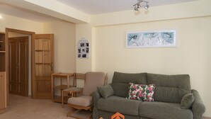 A living room with a grey sofa, a wooden chair, a small table, and a wall-mounted picture.