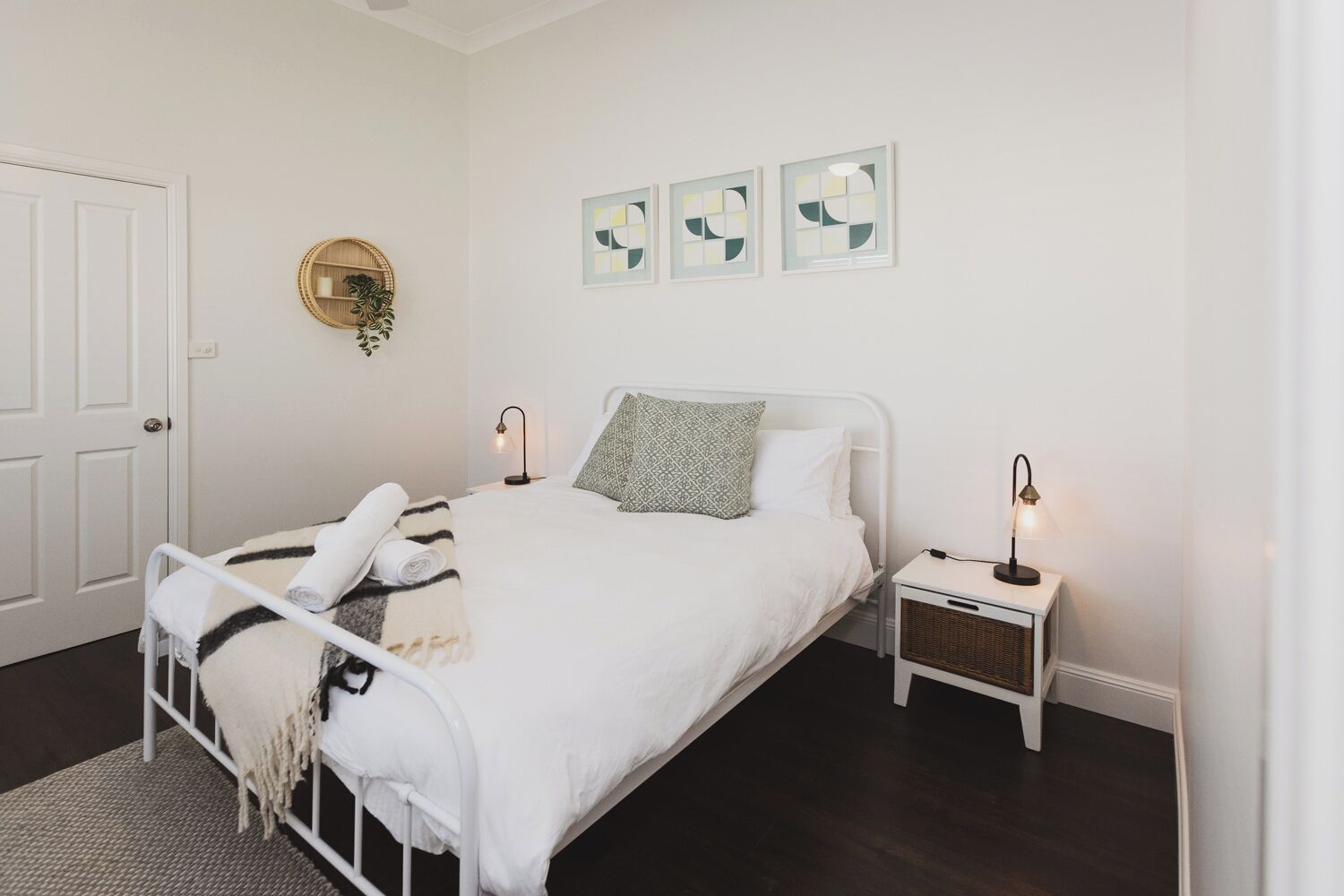 Un dormitorio ordenado con cama, mesitas de noche y decoración en la pared.