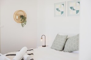 Un dormitorio minimalista con cama, planta en la pared, lámpara y arte abstracto.