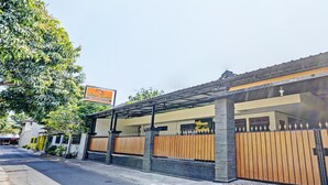A building with a covered entrance, a gated driveway, and a signboard. - OYO Life 92785 Wisma Trubus  Syariah (Tuban)