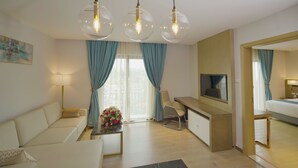 A modern hotel room with a sofa, a desk, a TV, and a dining area. - Stay Easy Plus Hotel (Addis Ababa)