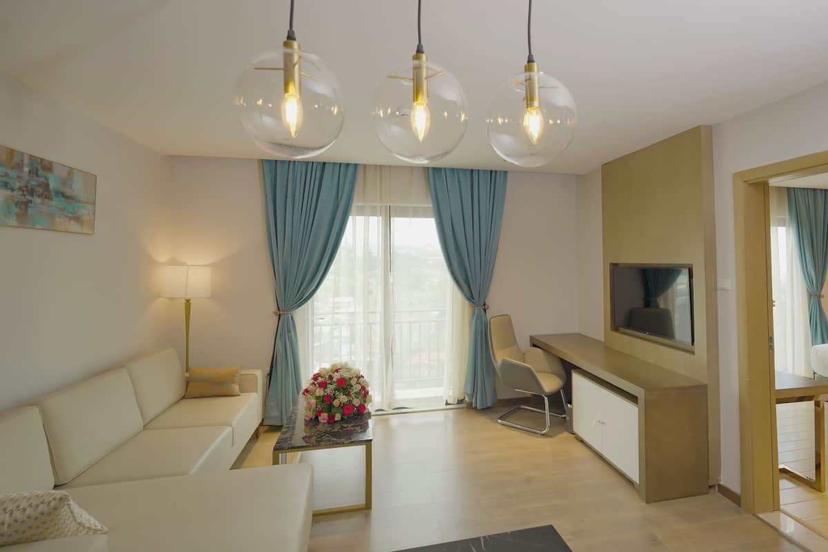 Ein modernes Hotelzimmer mit Sofa, Schreibtisch, Fernseher und Essbereich.