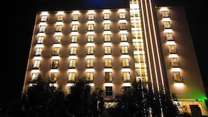 A multi-story hotel with illuminated windows and balconies, a 'Stay Easy' sign, and a green-lit entrance. - Stay Easy Plus Hotel (Addis Ababa)