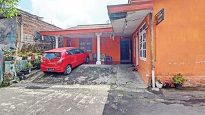 Un coche rojo estacionado frente a un edificio con techo rojo y una columna blanca.