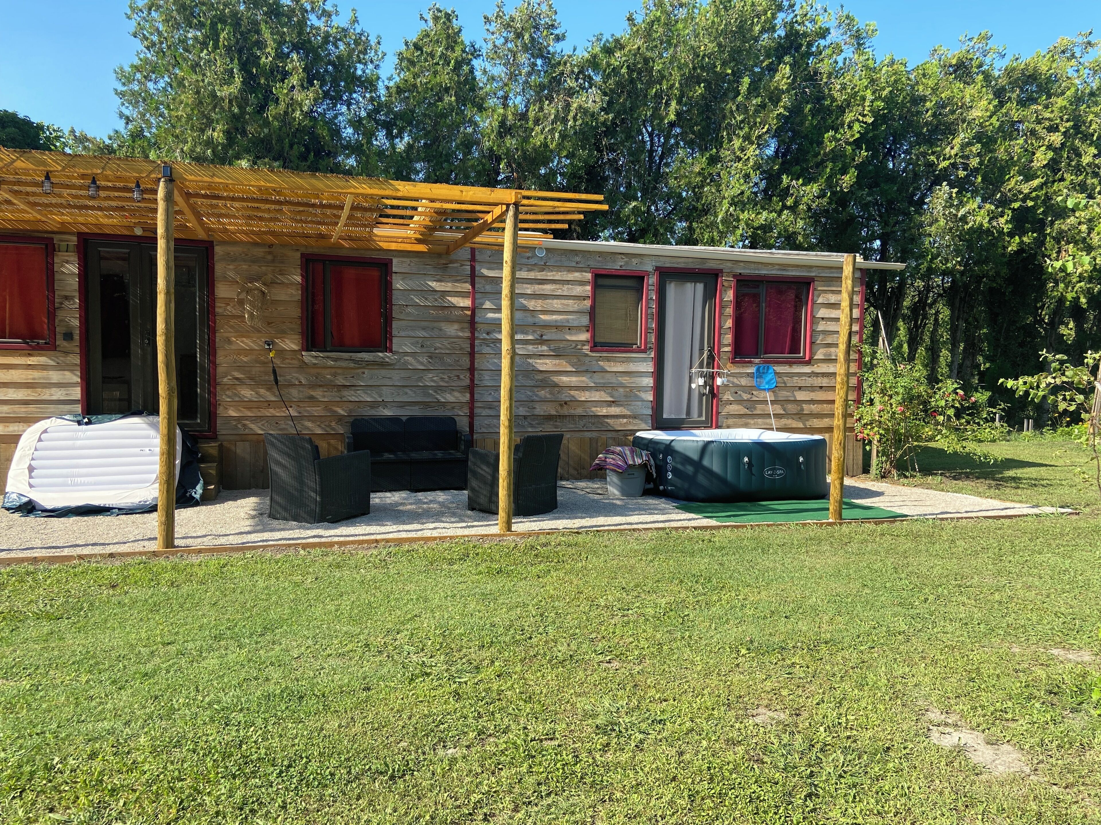 A wooden cabin with a covered patio, outdoor seating, and a hot tub.