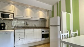 A kitchen with white cabinets, a microwave, a stove, and a refrigerator.