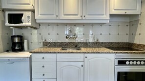 A kitchen with white cabinets, a granite countertop, a built-in microwave, a coffee maker, a sink, and a dishwasher. - SALLES BEACH 5 (Estartit)
