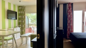 Ein Zimmer mit Bett, Fernseher, Schreibtisch und Stuhl.