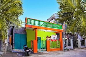 A building with a green and orange facade, a balcony, and a motorcycle parked in front.