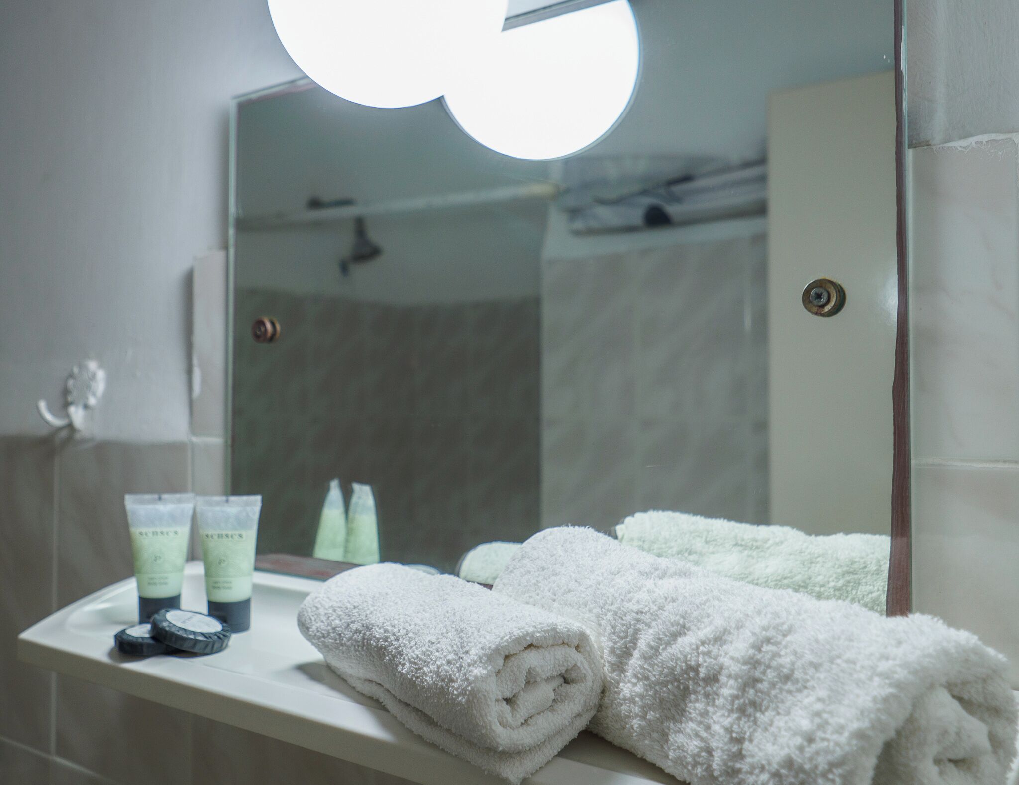 A bathroom with a white sink, two bottles of lotion, and two towels.