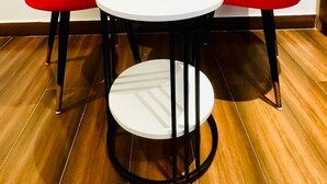 Two red chairs and a white table with black legs in a room with wooden flooring. - Hotel Primrose - Patiala (Pantran)