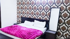 Une chambre d’hôtel avec un lit, une table de chevet, un miroir et un mur décoré d’un motif.