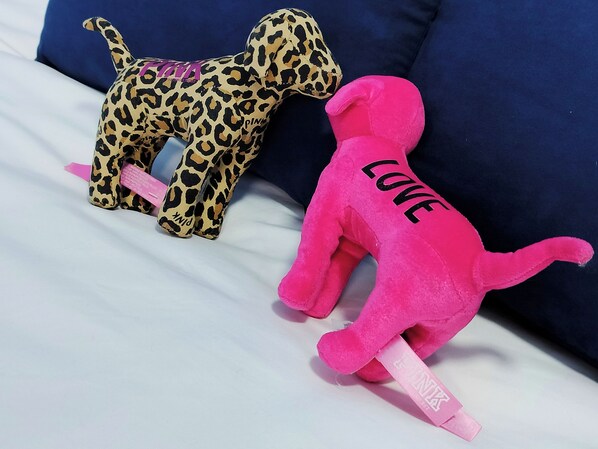 Deux peluches sur un lit, avec un oreiller en arrière-plan.
