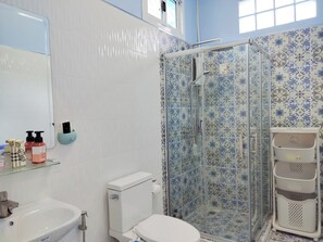 Une salle de bain avec un lavabo blanc, des toilettes et une douche, le tout agrémenté de carreaux bleus à motifs.