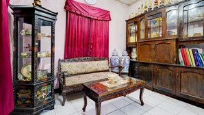 Un salón tradicional con un sofá, una mesa de centro, una vitrina y un reloj en la pared.