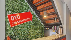 A reception area with a red sign indicating 'OYO J&B SMART SENTUL'. - Capital O 92765 J&b Smart Sentul (Citaringgul)