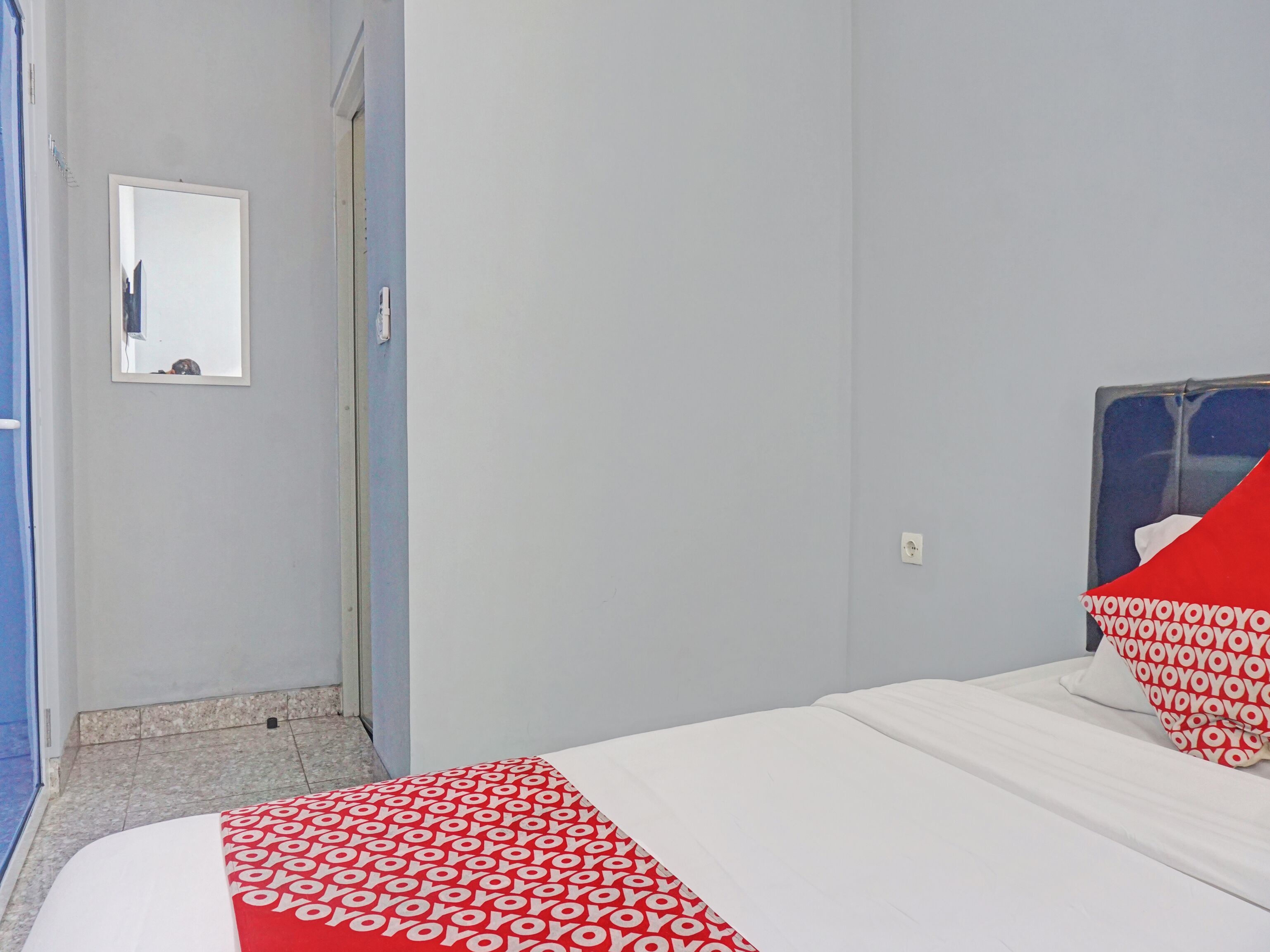 A hotel room with a bed, a mirror, and a door.