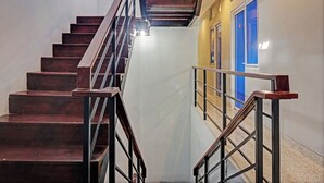 A staircase with wooden steps and metal railings, leading to a landing with a blue door and a window. - Capital O 92765 J&b Smart Sentul (Citaringgul)