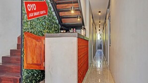 A hallway with a wooden staircase, a reception desk, and a sign for J&B Smart Sentul. - Capital O 92765 J&b Smart Sentul (Citaringgul)