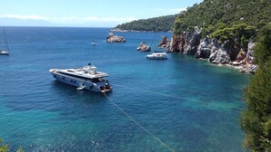 Un paysage côtier avec un yacht ancré près de falaises rocheuses et d’eaux bleues et limpides.