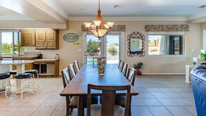 A spacious kitchen with wooden cabinets, a central island, and a dining area with a long table and chairs. - Havasu Paso - Pool, Spa, Games, Mountain Views (Lake Havasu City)