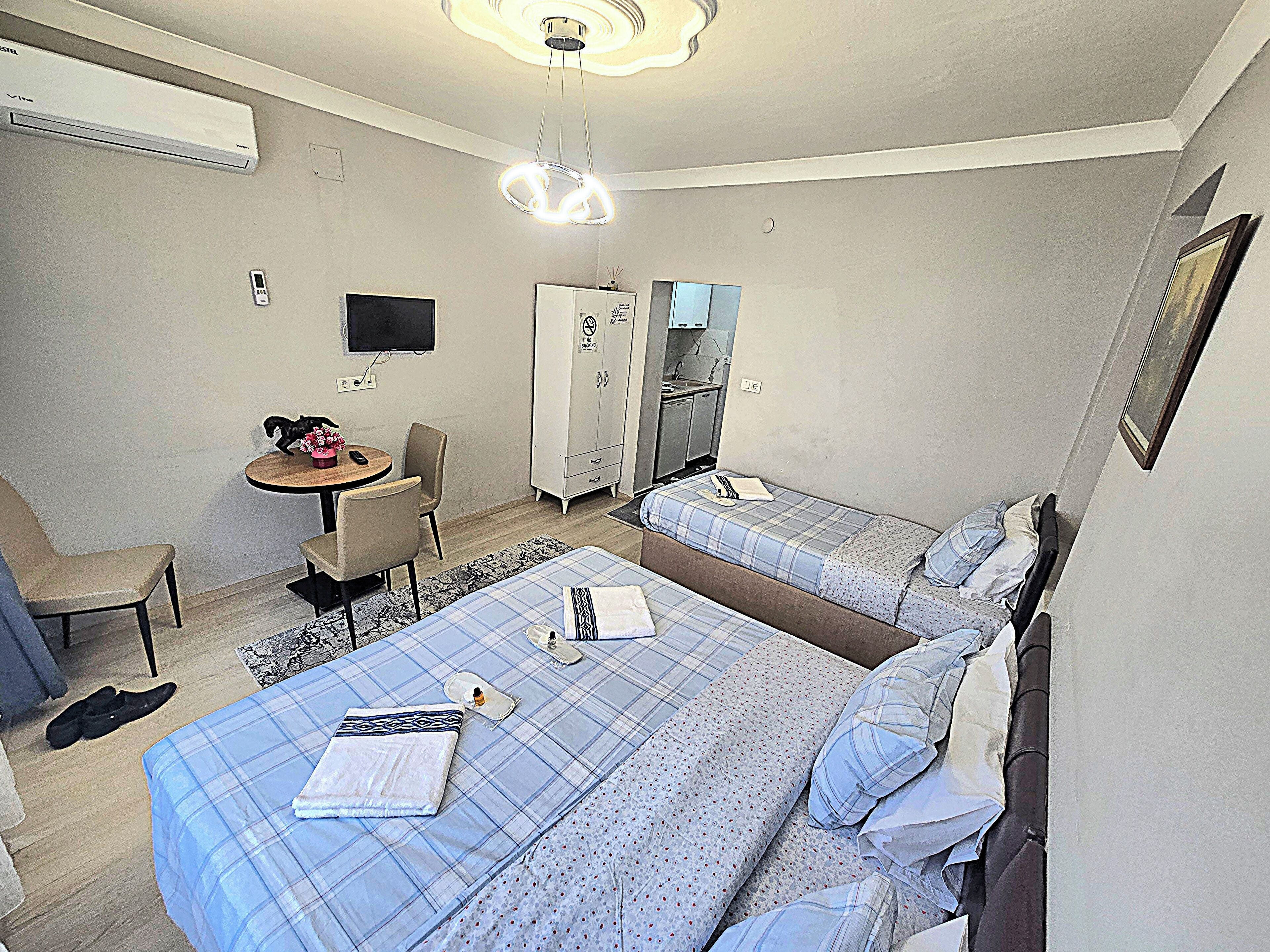 A hotel room with two beds, a desk, a chair, a wardrobe, and a television.