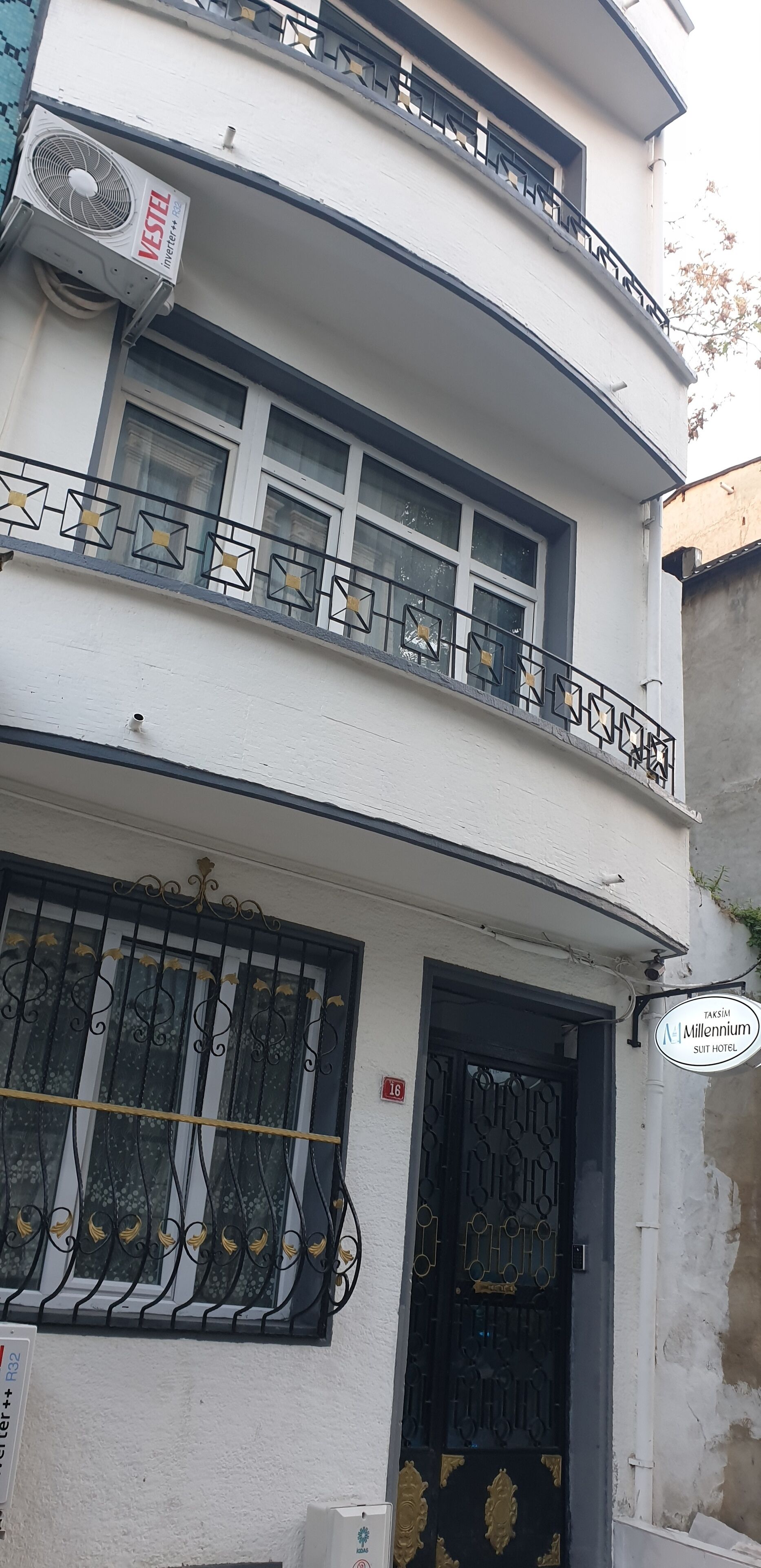 Un edificio di due piani con un balcone, un cancello nero e un cartello per Taksim Millenium Suit Hotel.