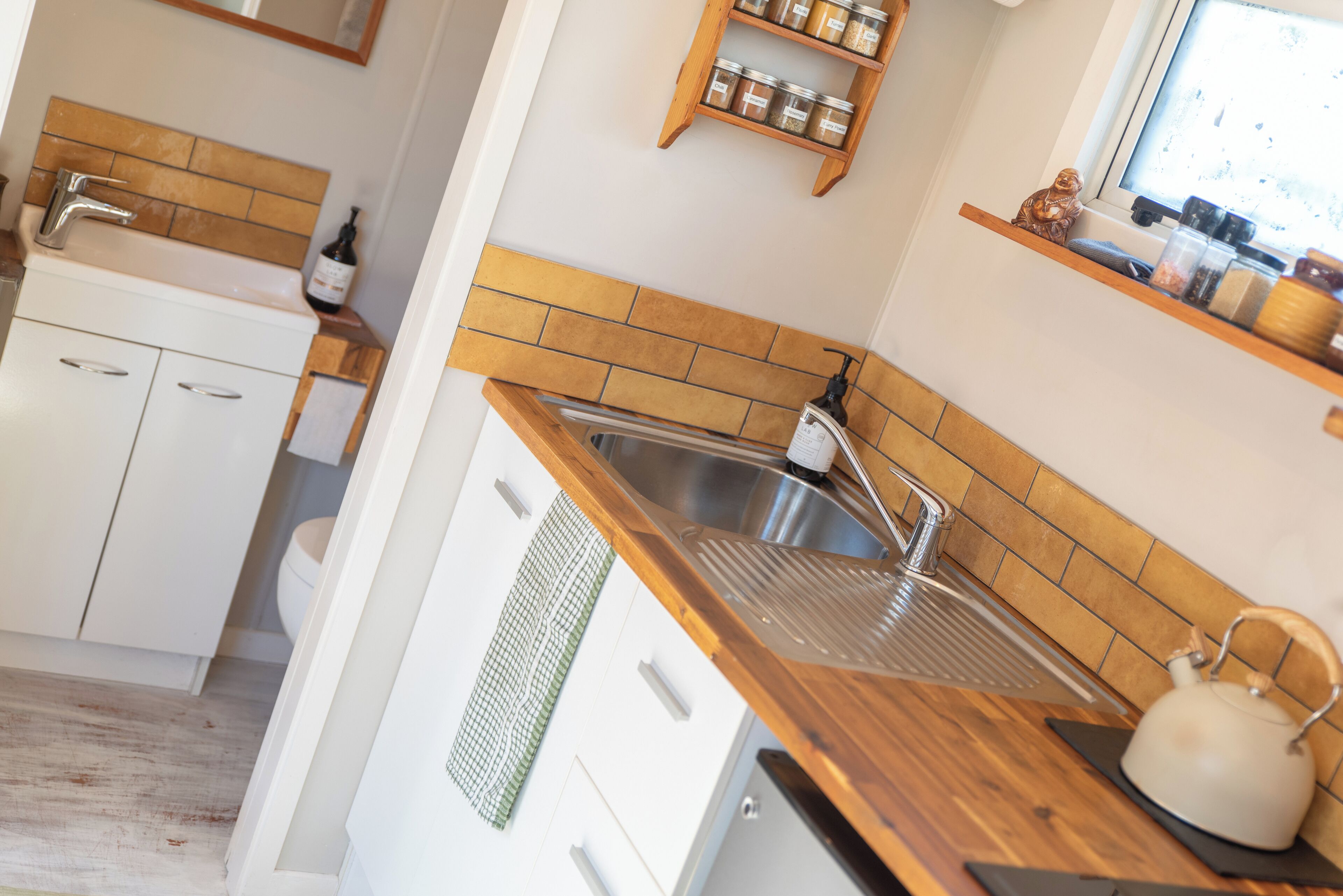 A modern kitchen with a wooden countertop, stainless steel sink, and a window above the sink.