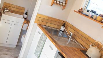 A modern kitchen with a wooden countertop, stainless steel sink, and a window above the sink.