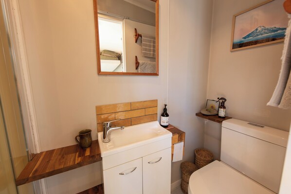 A bathroom with a wooden vanity, a white sink, a mirror, and a toilet.